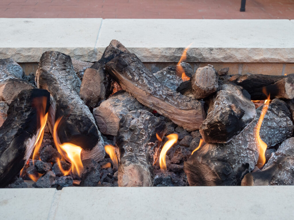 Logs sitting in open fire in a white stone firepit
